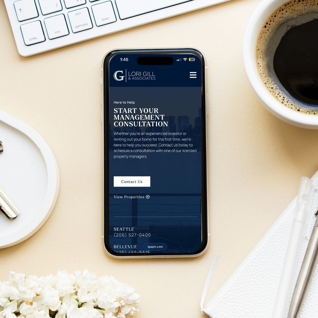 Smartphone on desk displaying property management consultation website with coffee and glasses