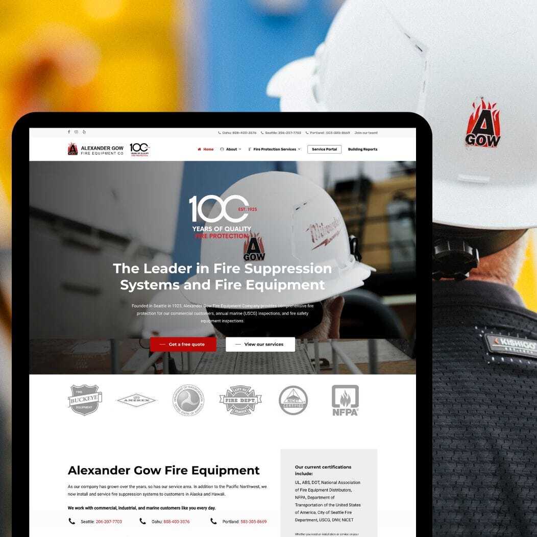 A website on a tablet screen displaying Alexander Gow Fire Equipment with a focus on fire suppression systems. The background shows a worker in a hard hat with a company logo. .