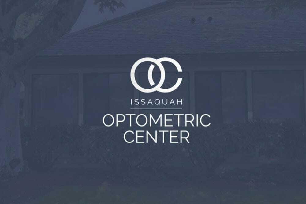 Logo of Issaquah Optometric Center featuring stylized overlapping letters O and C above the text. The background is a darkened image of a building with windows, partially visible due to the logo overlay.