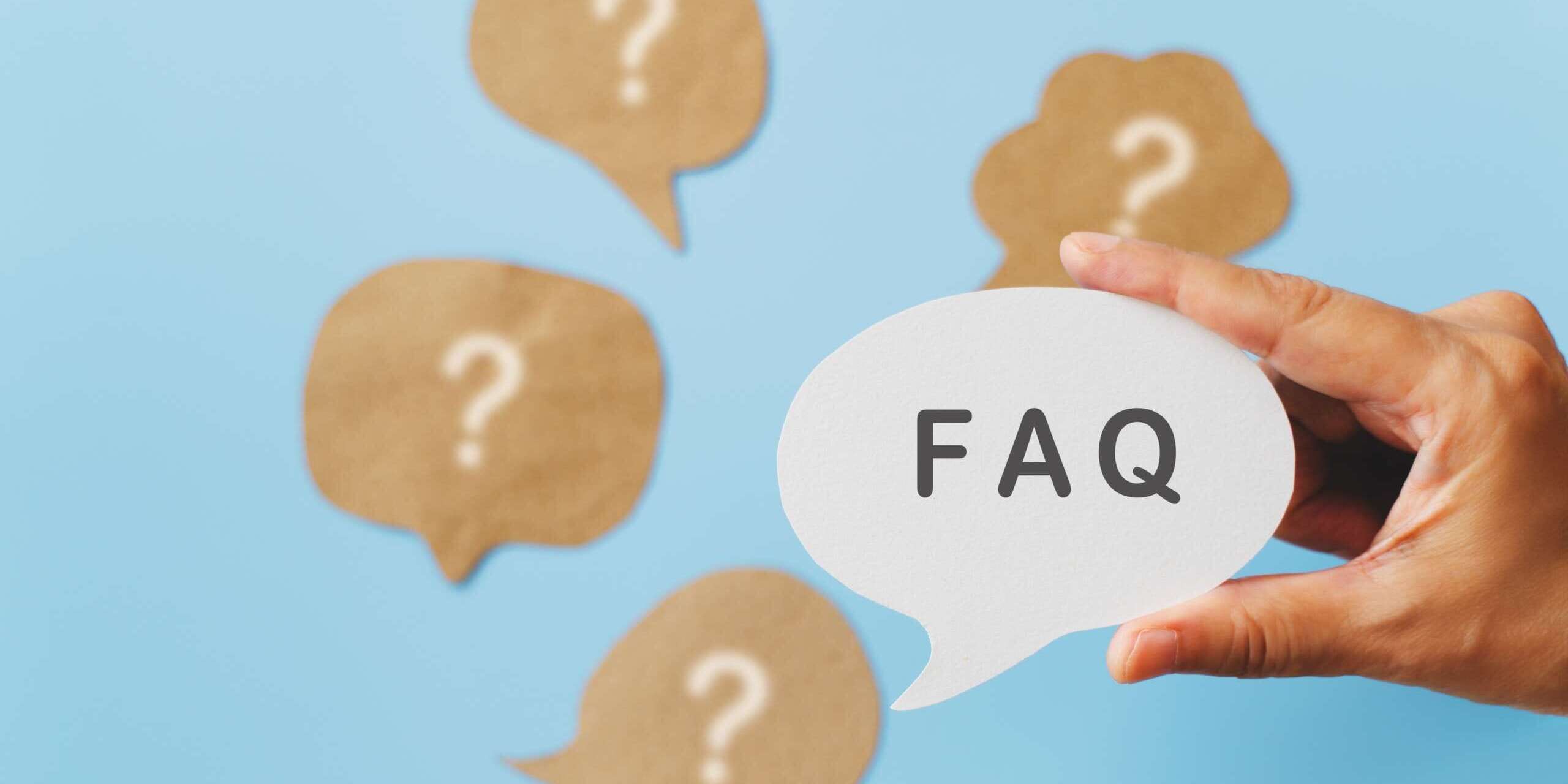 A hand holds a white speech bubble with FAQ written on it against a blue background. Surrounding it are several brown speech bubbles with question marks.