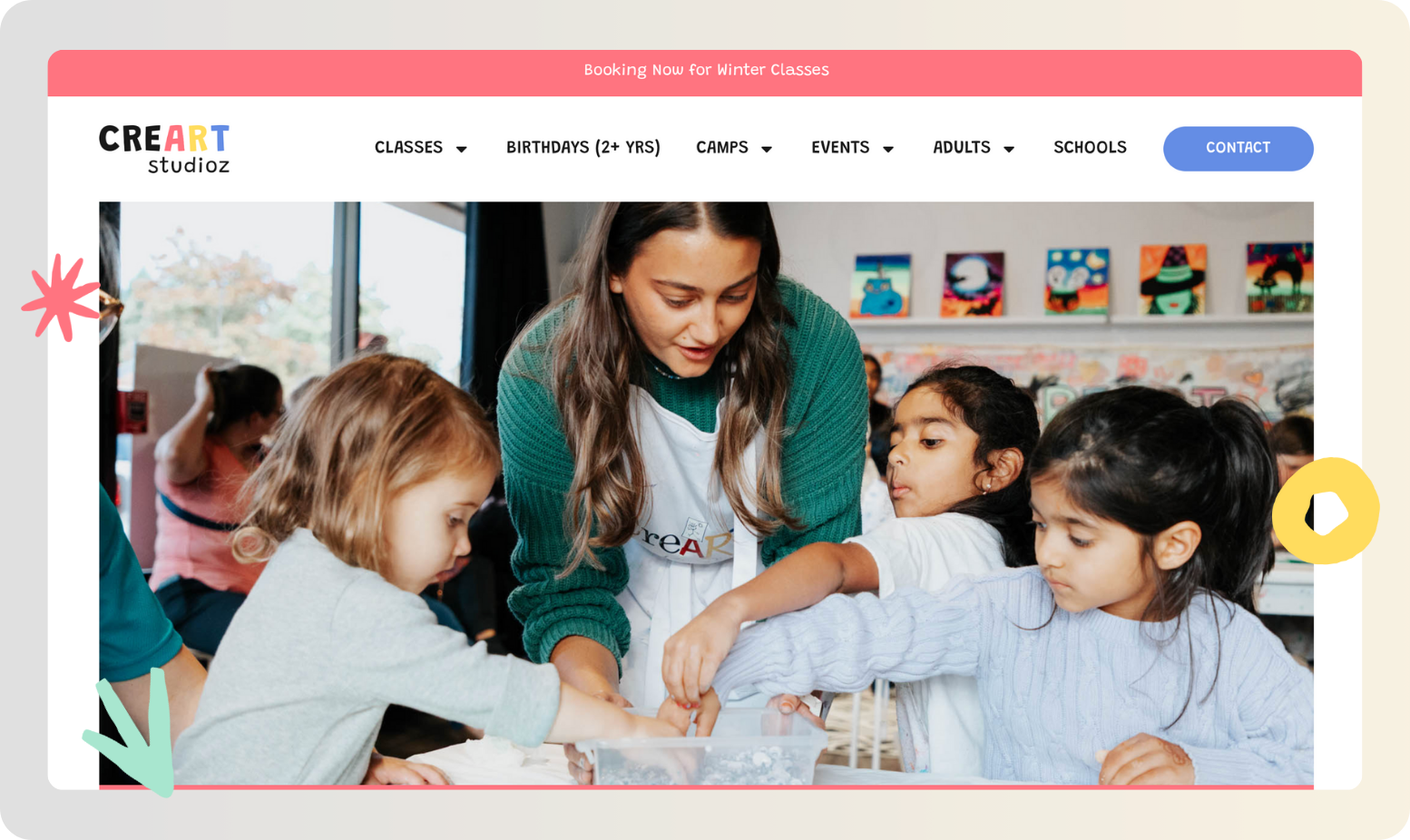 A woman helps three young children with an art project at a table in a bright, colorful art studio. Artworks are displayed on the wall in the background.